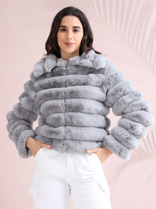 Woman wearing a stylish light grey faux fur puffer jacket with horizontal padded design, paired with white cargo pants.