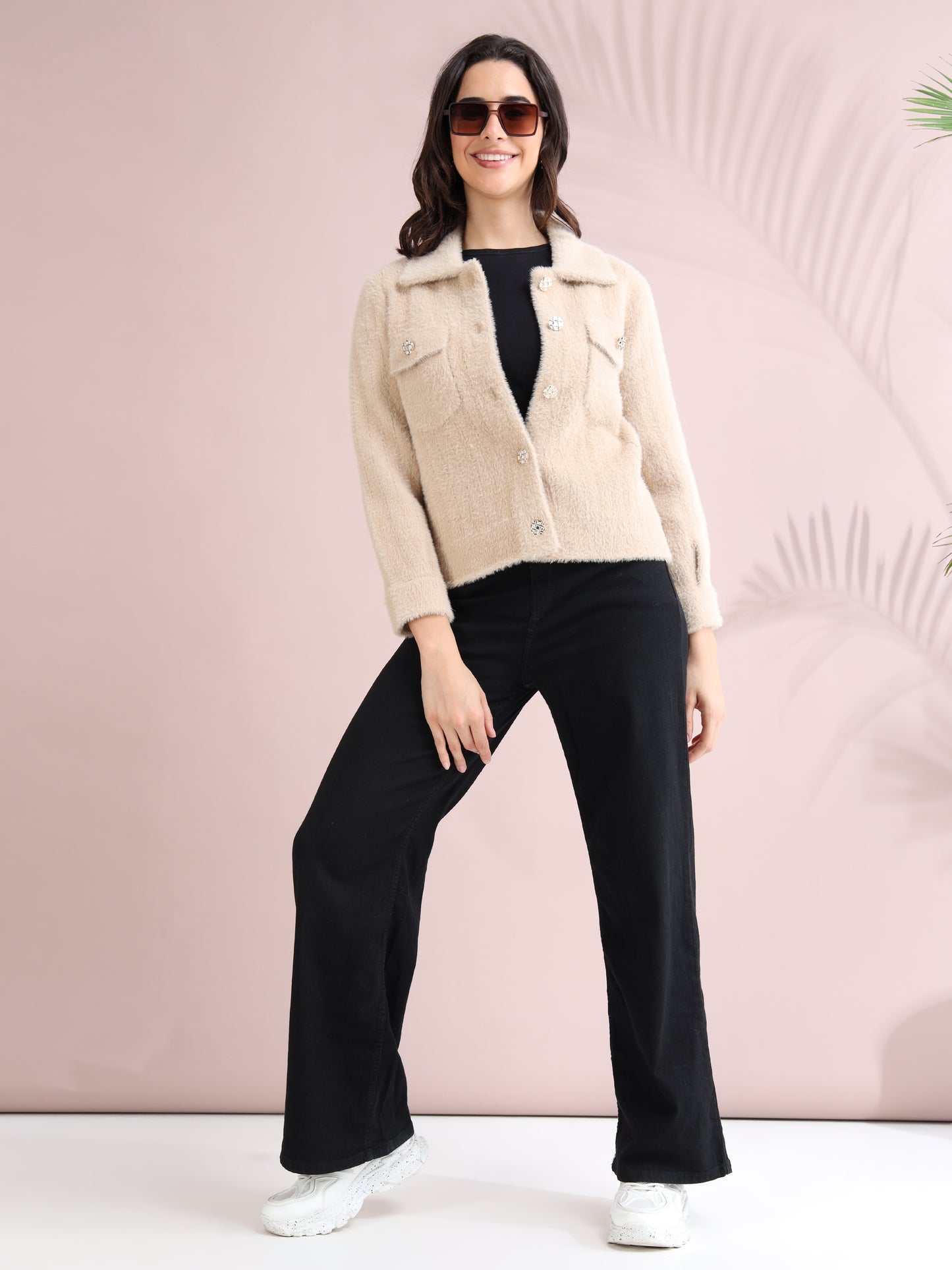 Women wearing beige button-down fuzzy jacket styled with black wide-leg pants and white sneakers.