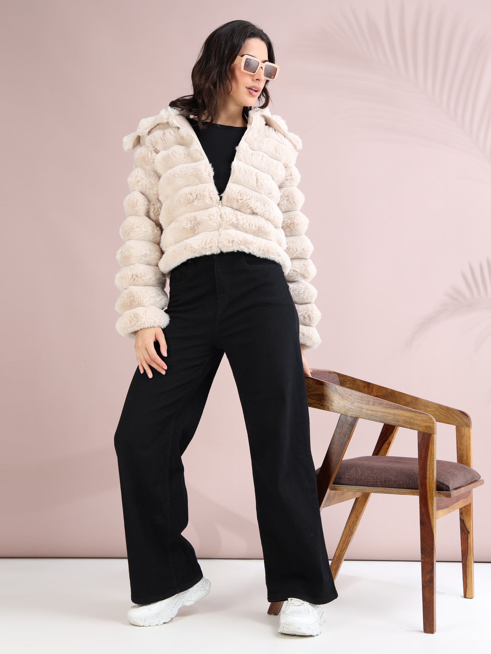 Women styling beige faux fur jacket with black wide-leg pants and white sneakers