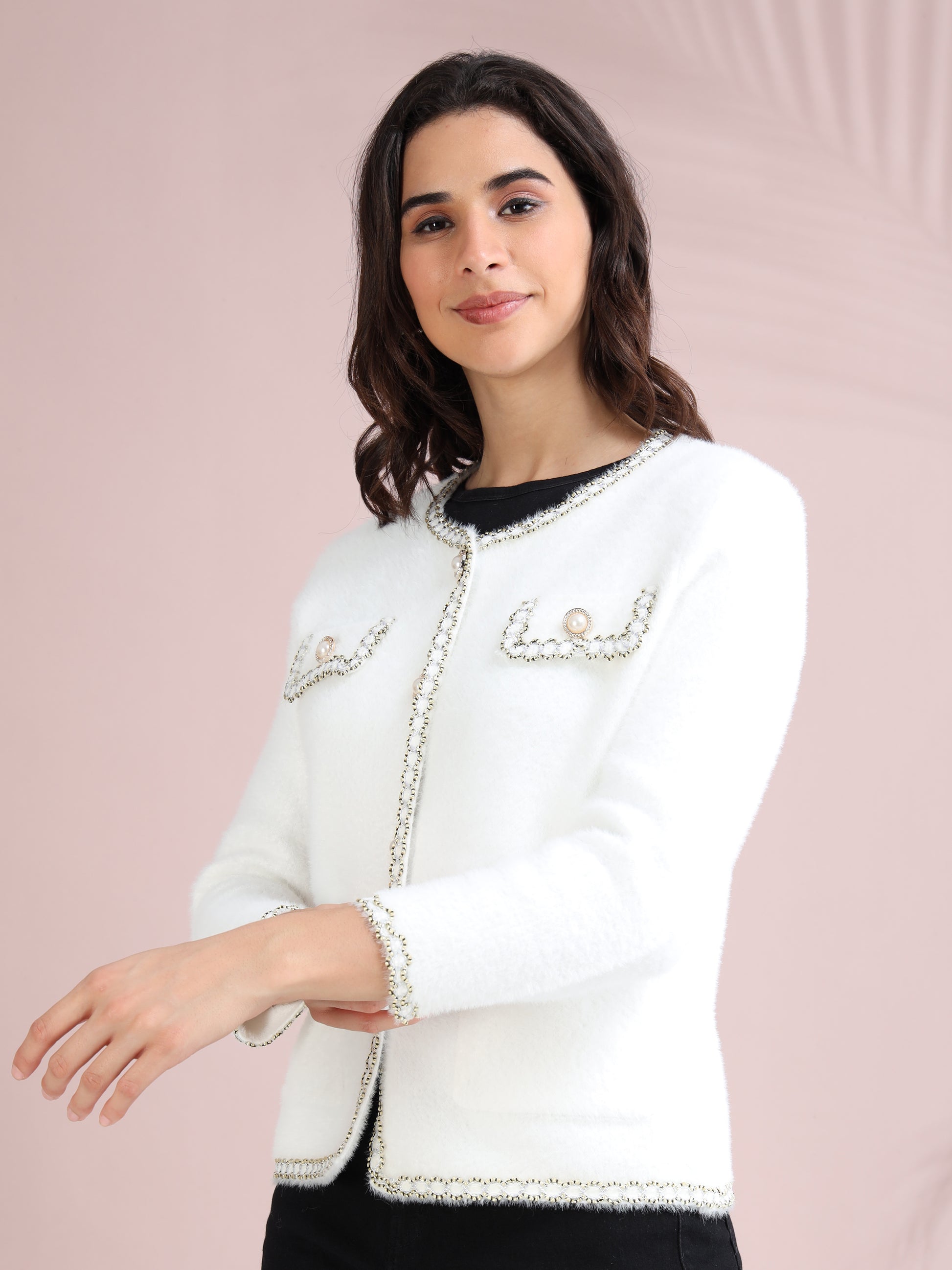 Side profile of woman in white pearl button embellished cardigan with detailed edging and front pockets.