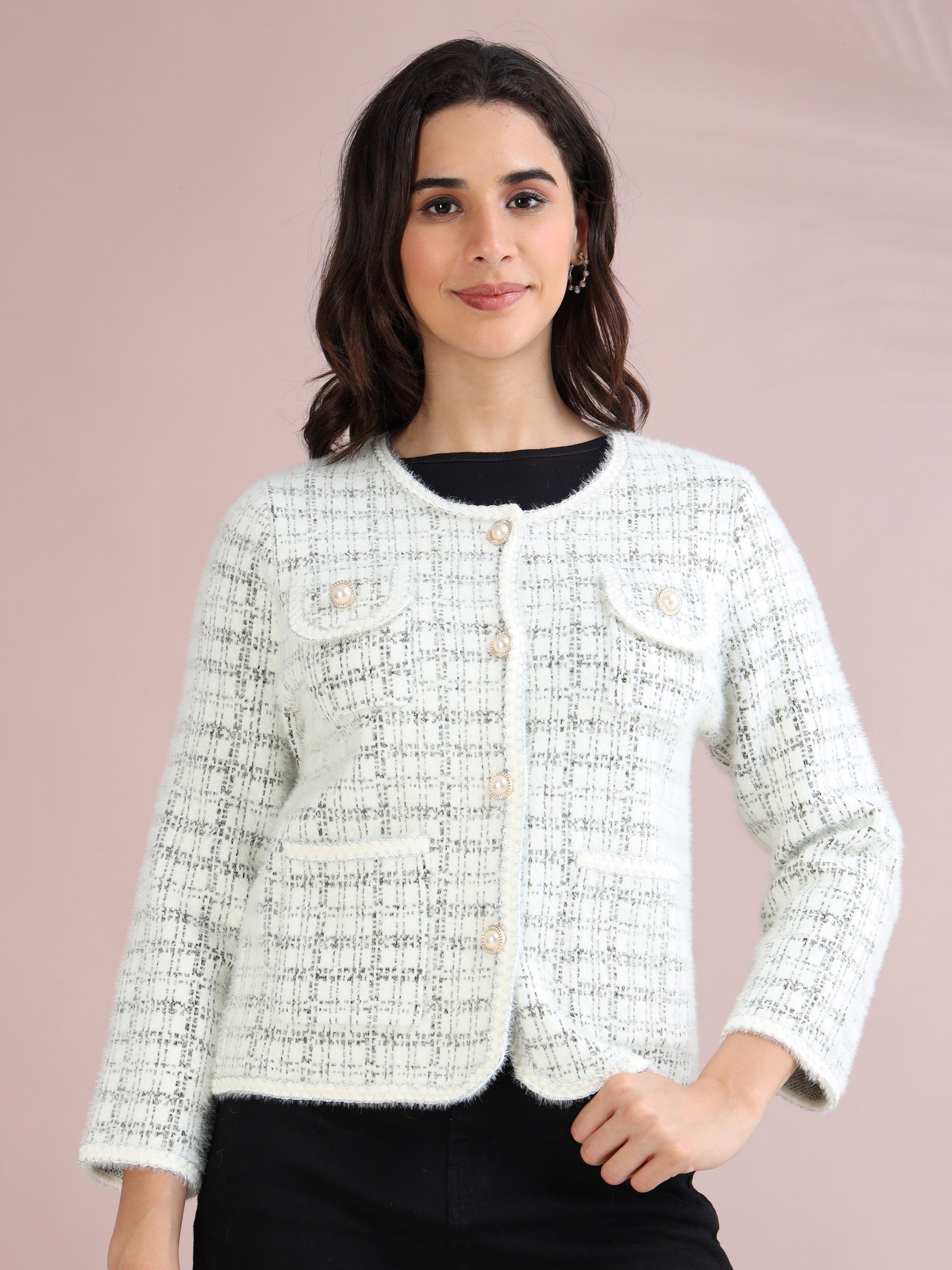 Woman wearing a white check tweed cardigan sweater with pearl button closure and front pockets.