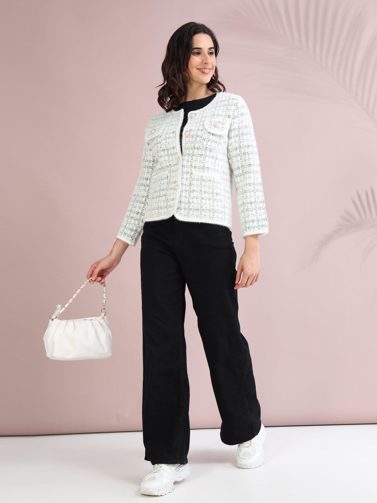 Woman styling a white check tweed cardigan with black trousers, white sneakers, and a chic white handbag