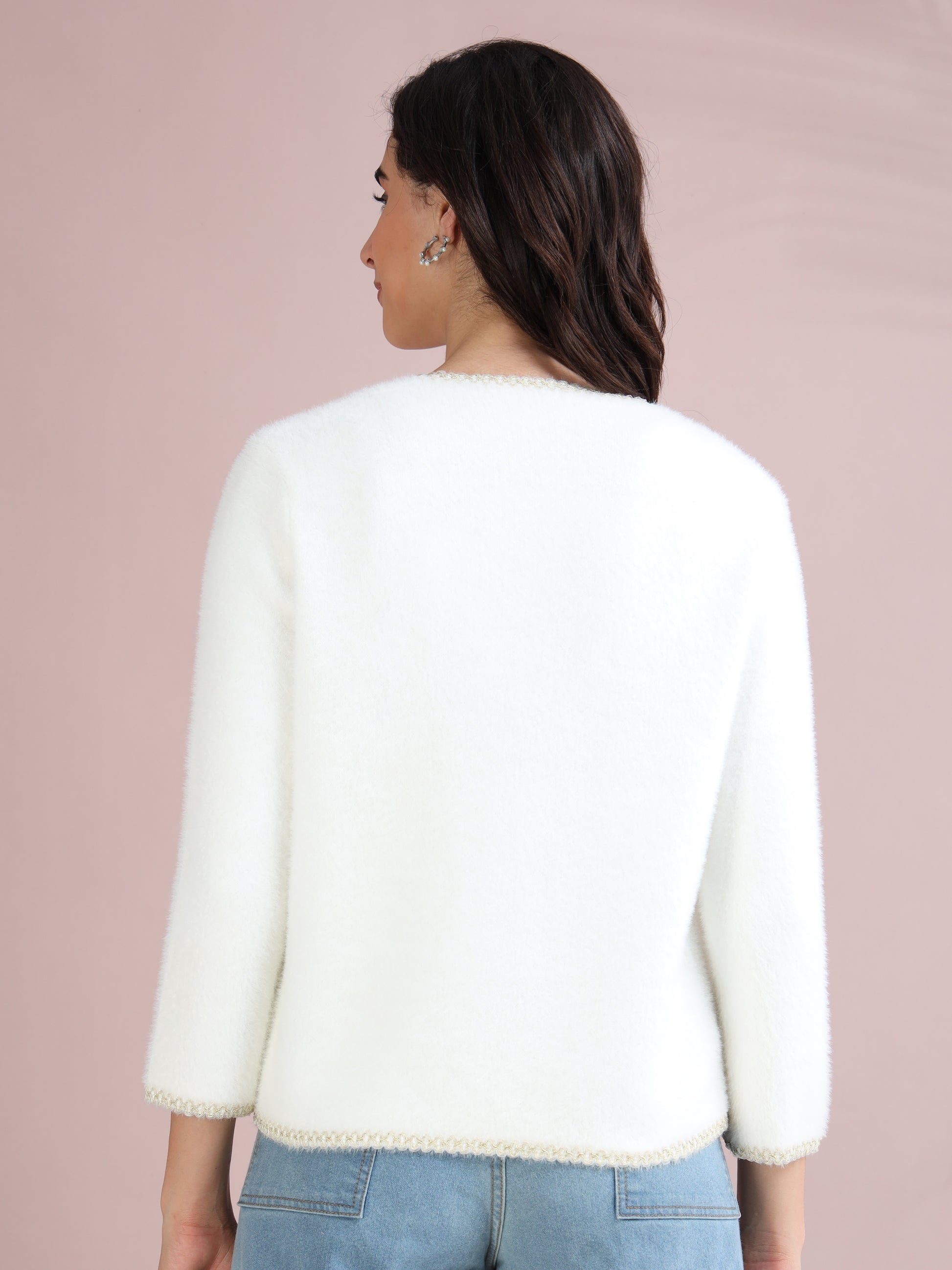 White women’s cardigan sweater with elegant pearl buttons and decorative trim, shown from side angle.