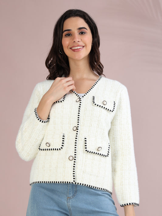 Woman wearing a white tweed cardigan with black trim and pearl-style buttons, styled with blue jeans.