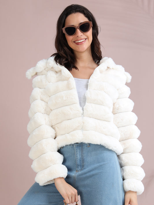 Woman wearing white faux fur puffer jacket with hood, styled with light blue jeans.