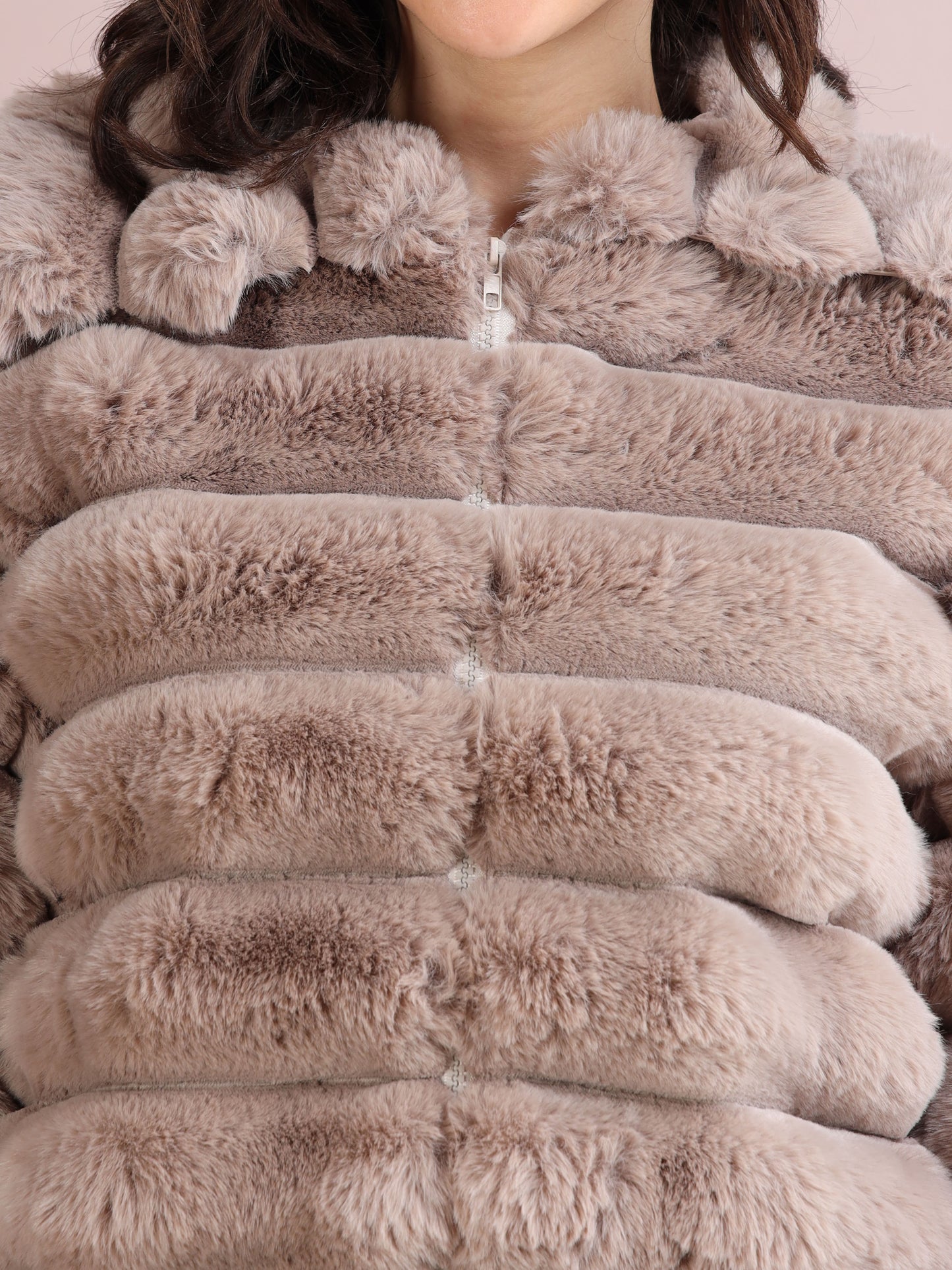 Detailed close-up of soft beige faux fur jacket texture with visible zipper and plush finish.