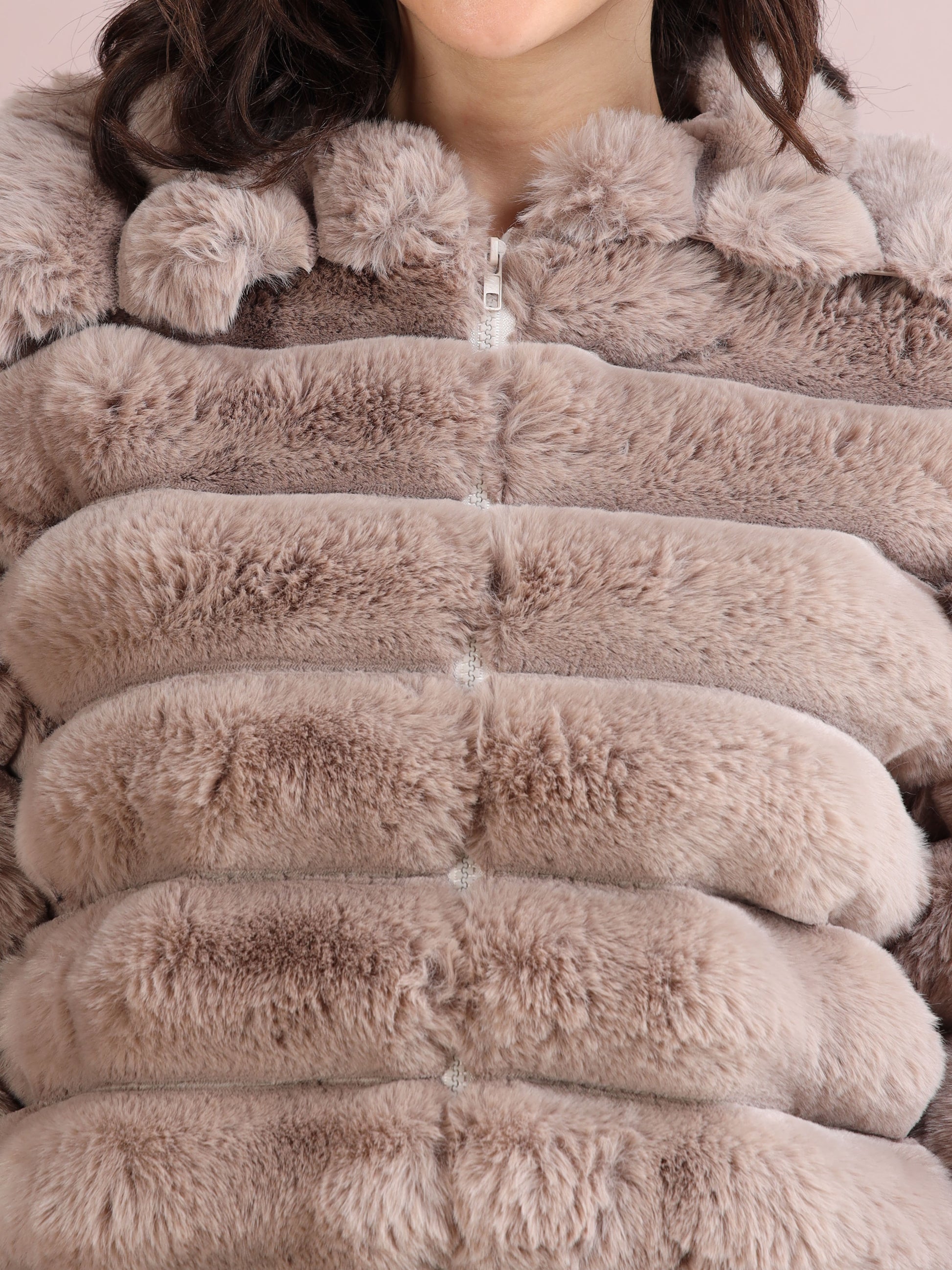 Detailed close-up of soft beige faux fur jacket texture with visible zipper and plush finish.