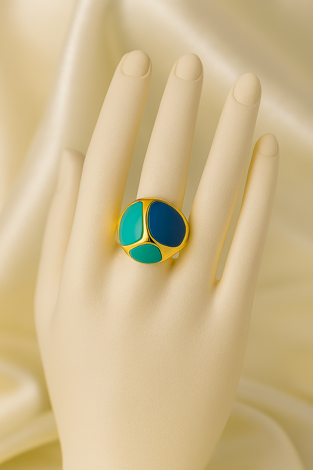 Gold-plated anti-tarnish ring with blue and green enamel inlays, worn on a mannequin