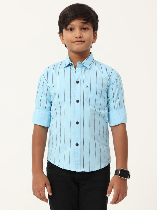 Child wearing a light blue striped shirt with black buttons on a white background