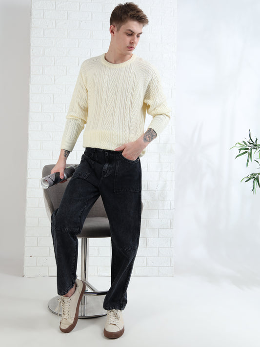 A person sitting on a stool wearing a mid-rise, button-closure, black denim jeans with four pockets.