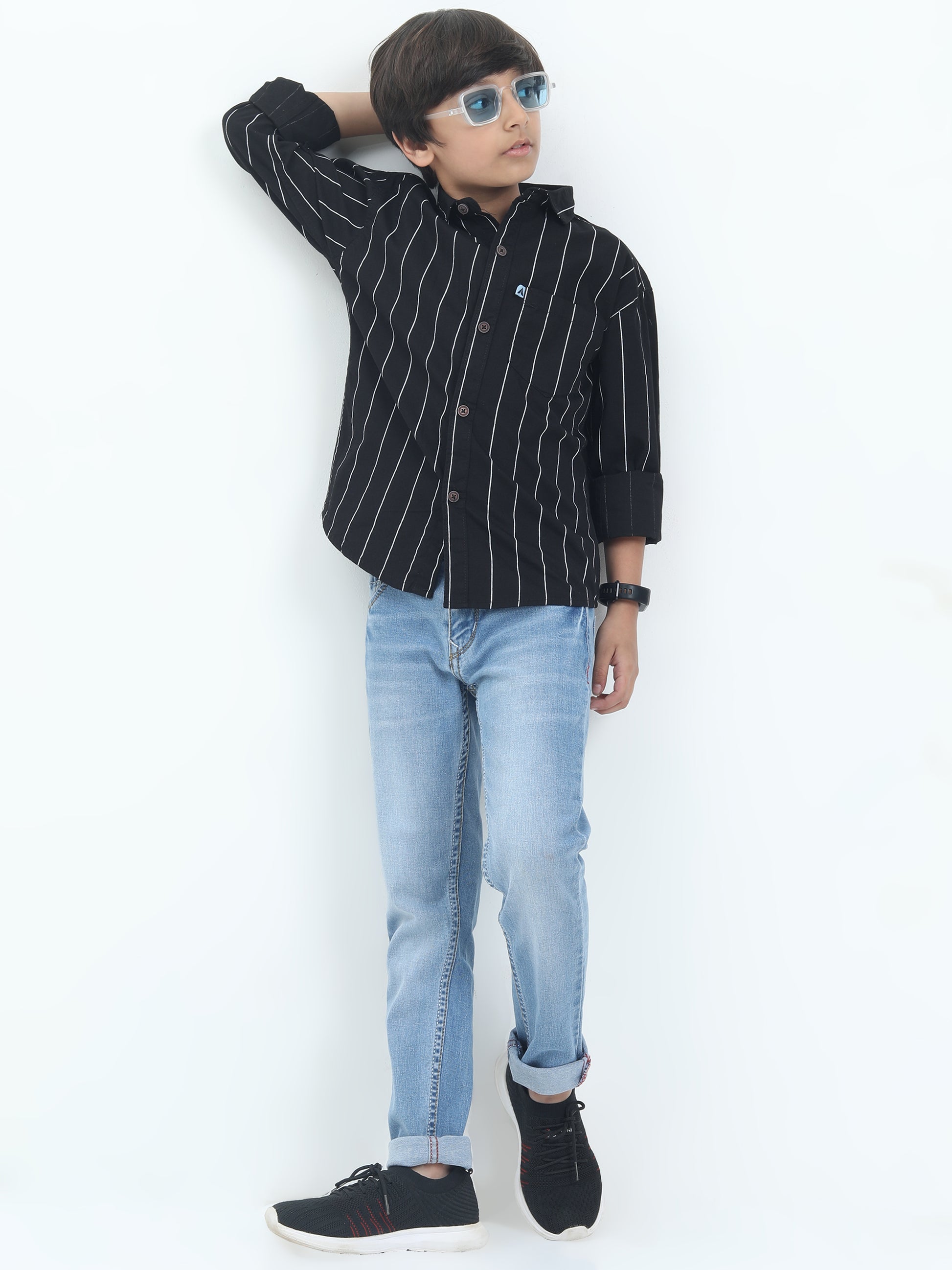 Child wearing a black striped shirt and light blue jeans on a white background