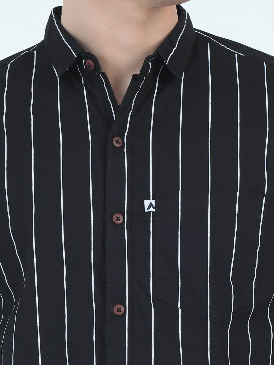 Black shirt with white vertical stripes and a small logo on a plain background
