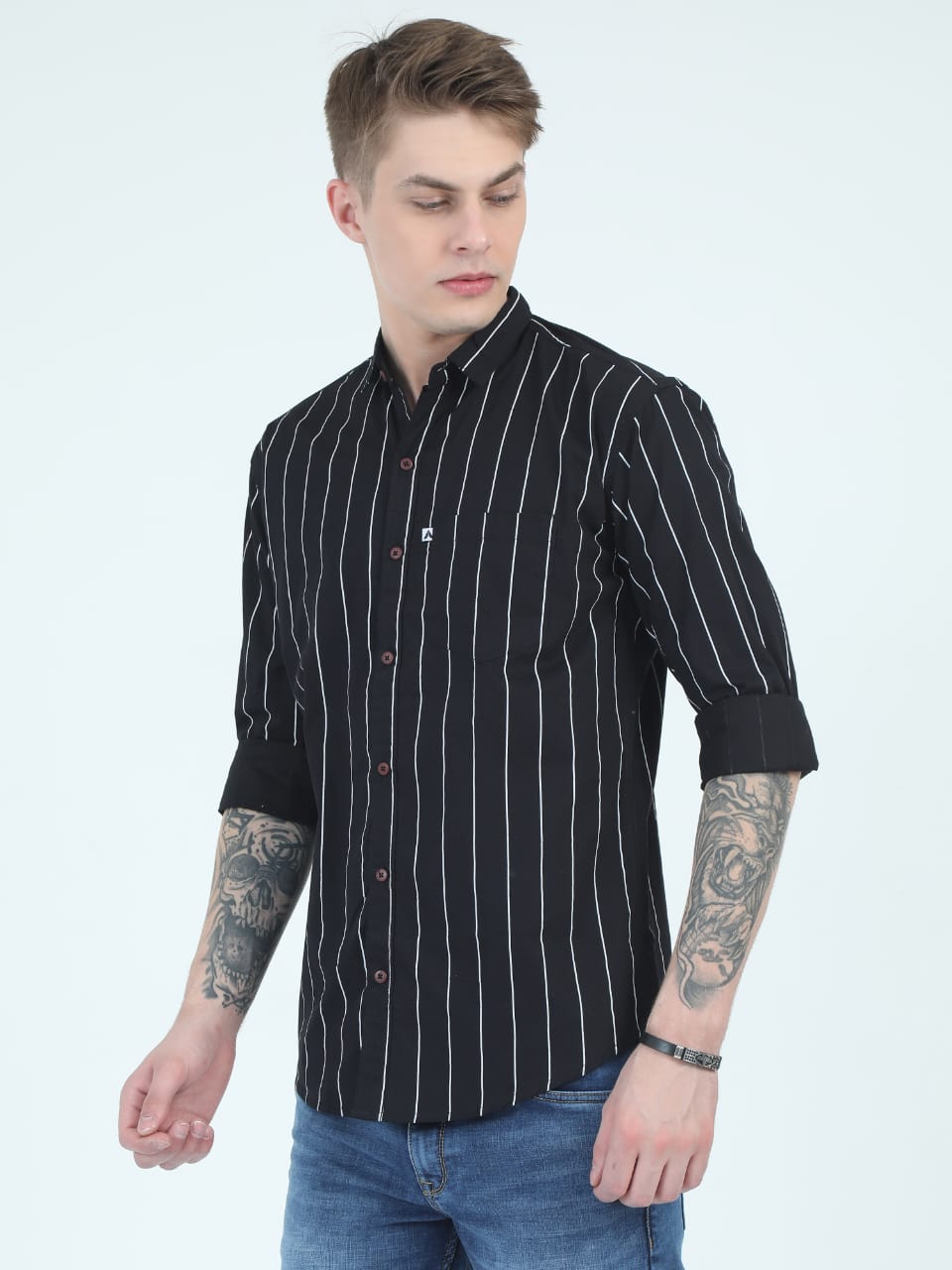 Man wearing a black and white striped shirt with rolled-up sleeves on a light gray background