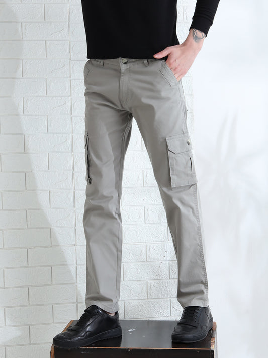 A person standing with hands in pockets, wearing smoke grey cargo pants with a relaxed fit and mid-rise design.