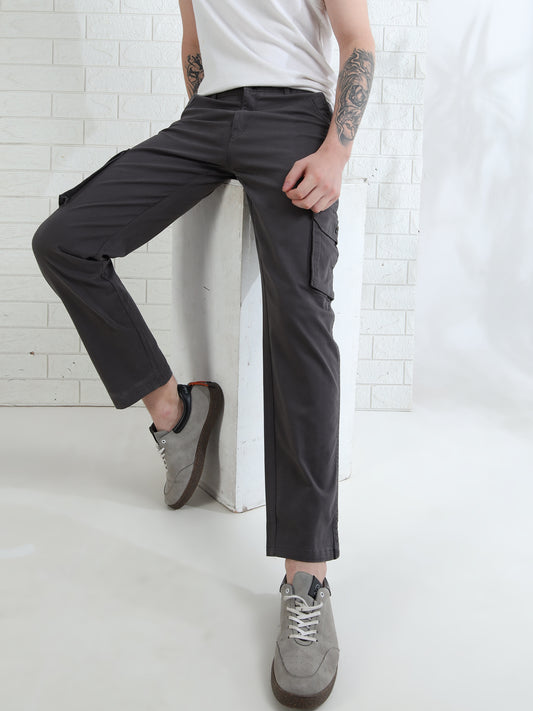 A person wearing dark grey cargo pants with six pockets, a white t-shirt, and gray shoes.
