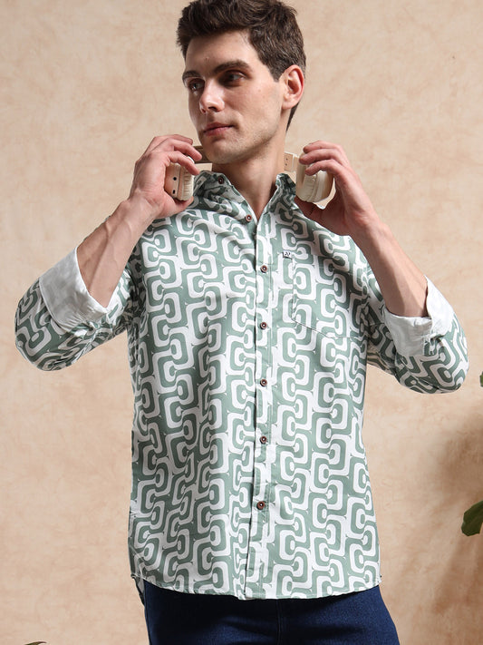 a green and white geometric printed shirt with folded sleeves, paired with dark blue jeans.