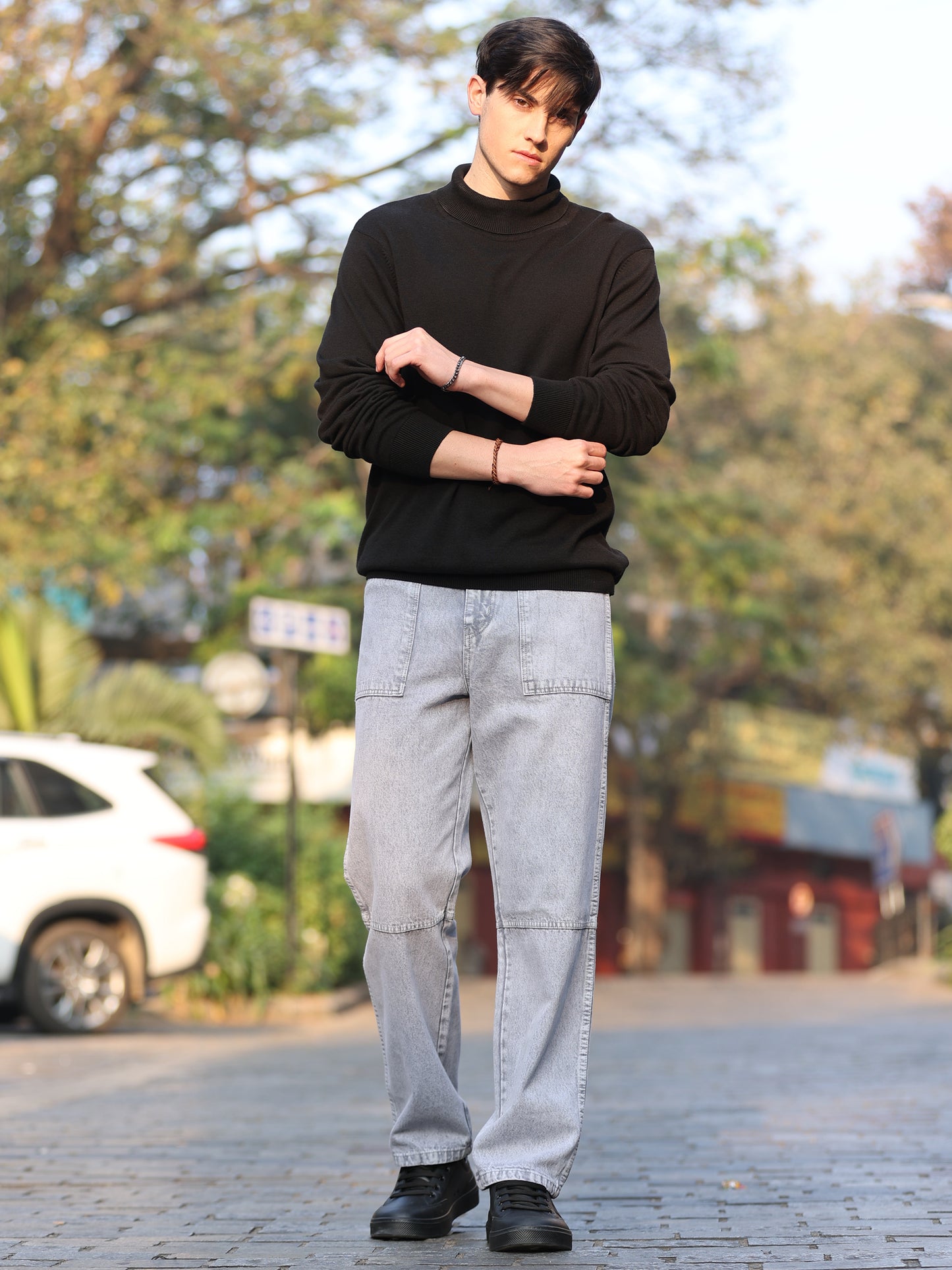 A person wearing light grey relaxed fit jeans with a mid-rise waist and a button closure.