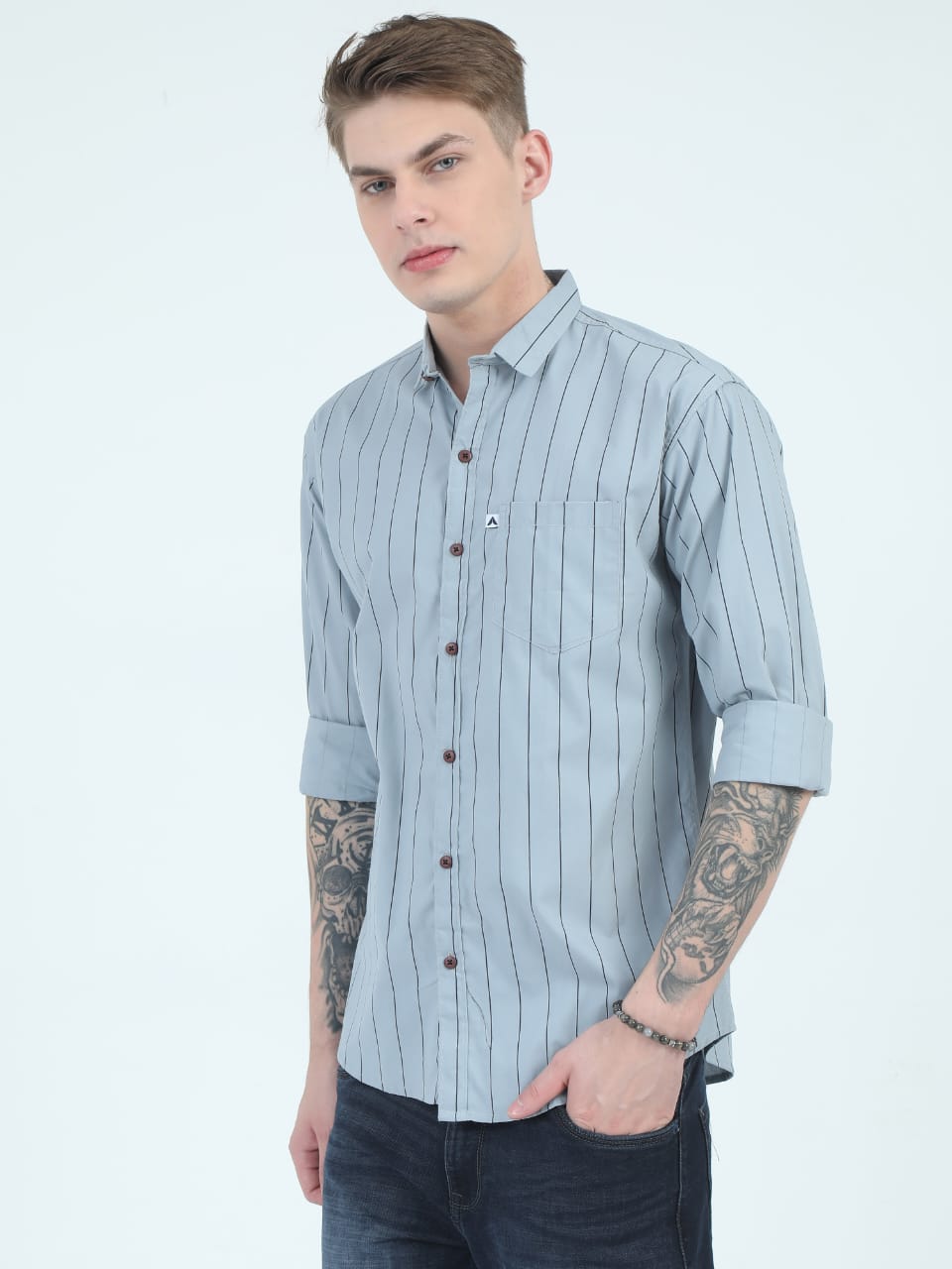 Man wearing a light blue striped shirt with rolled-up sleeves on a white background