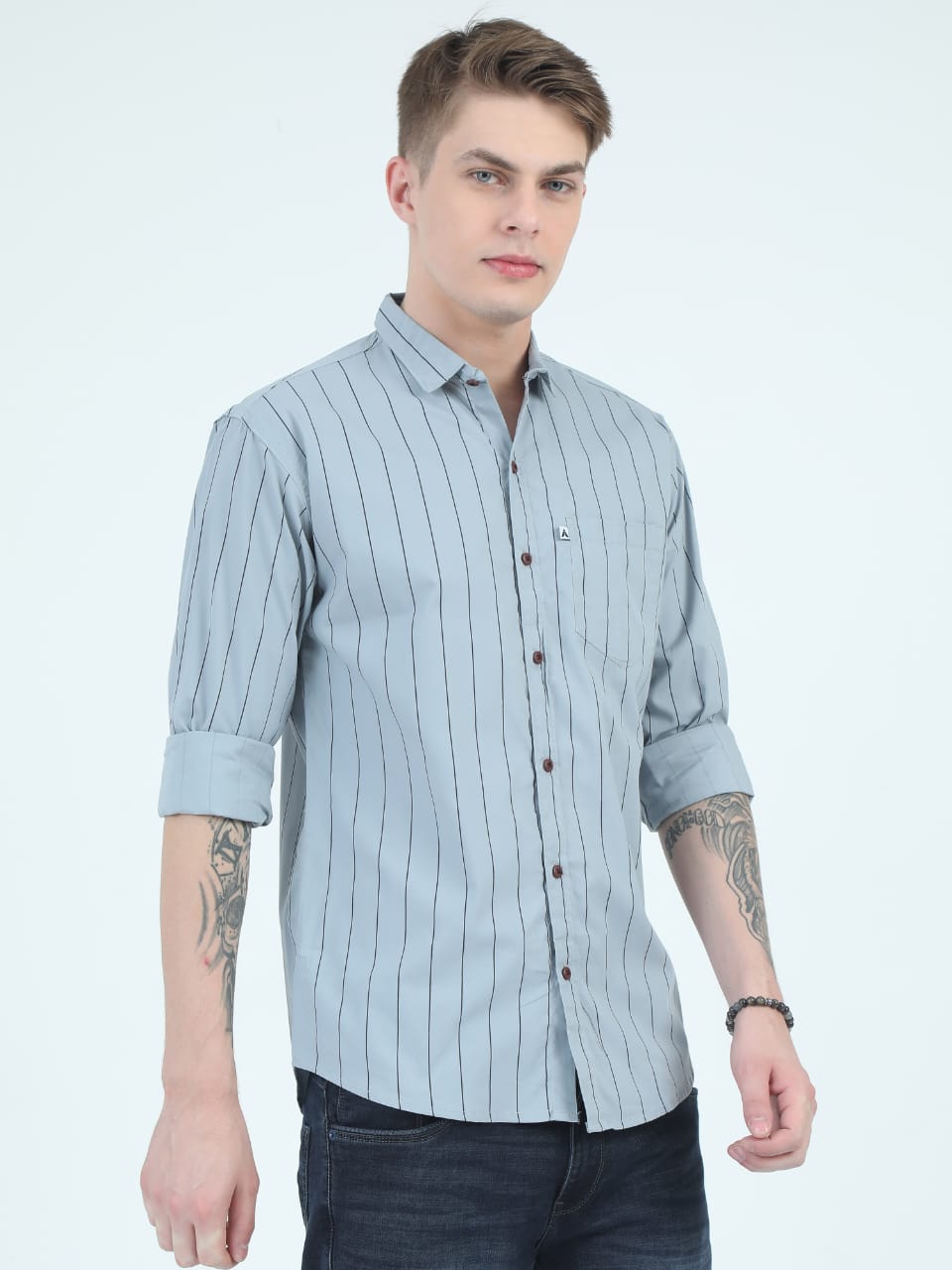 Man wearing a light blue striped shirt with rolled-up sleeves on a white background