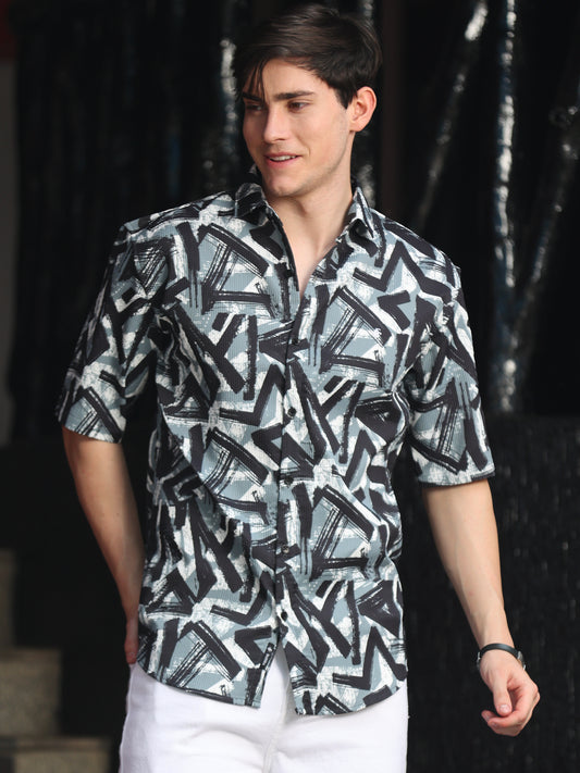 A man wearing a green geometric patterned shirt with half sleeves and a regular fit.