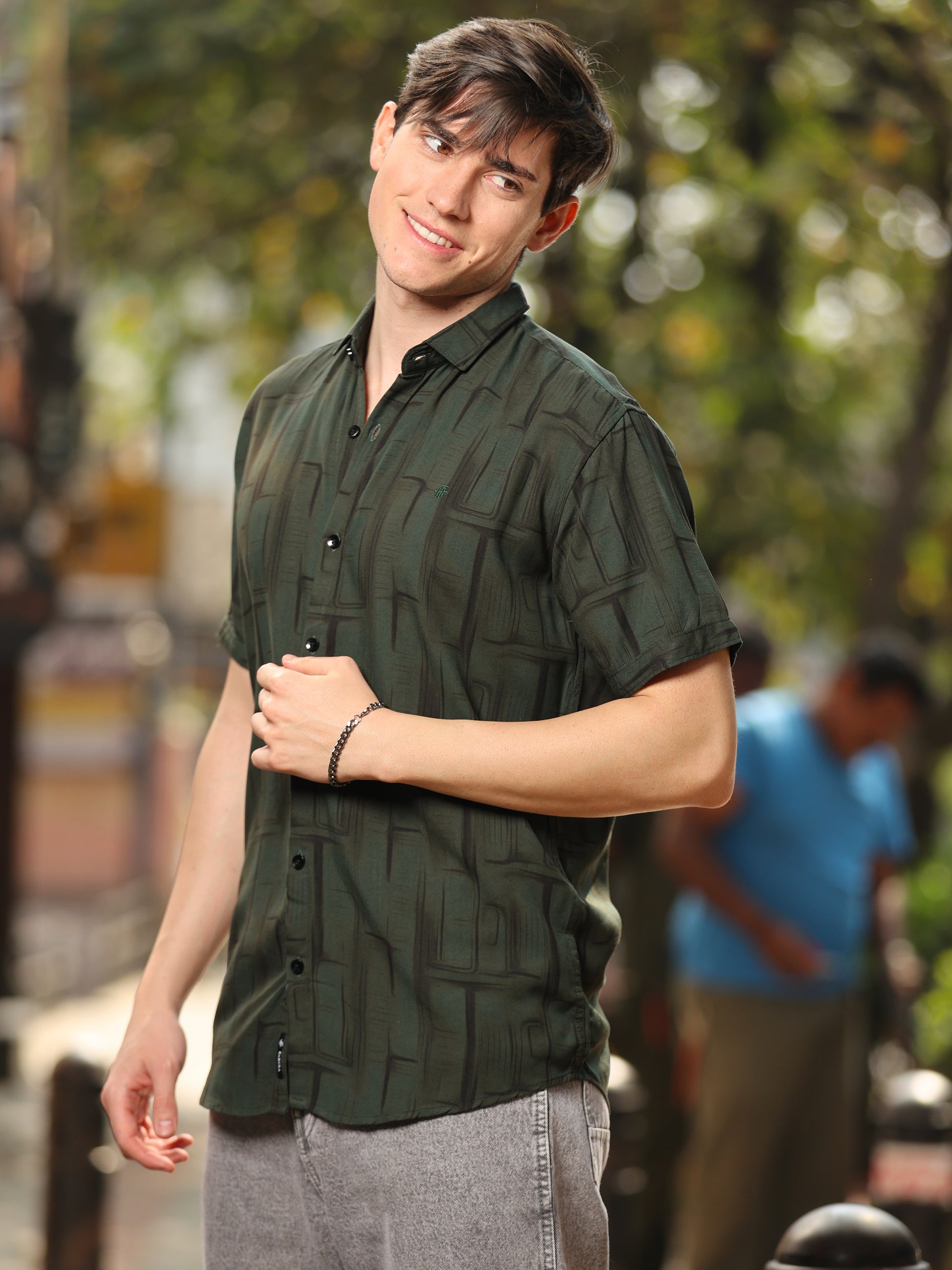 A man wearing a green rayon cotton printed shirt with half sleeves.
