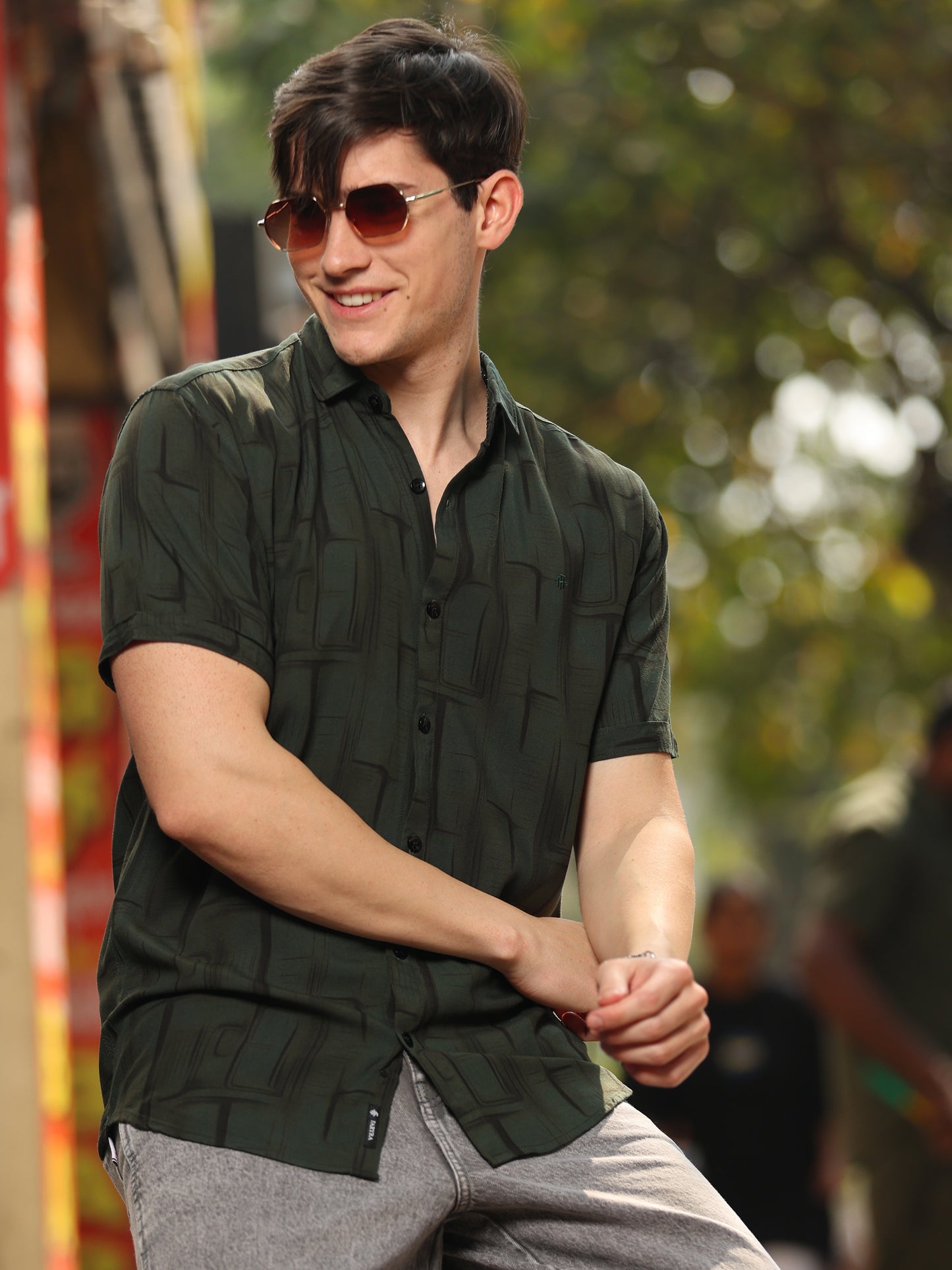 Casual men's printed green shirt paired with grey jeans in outdoor setting