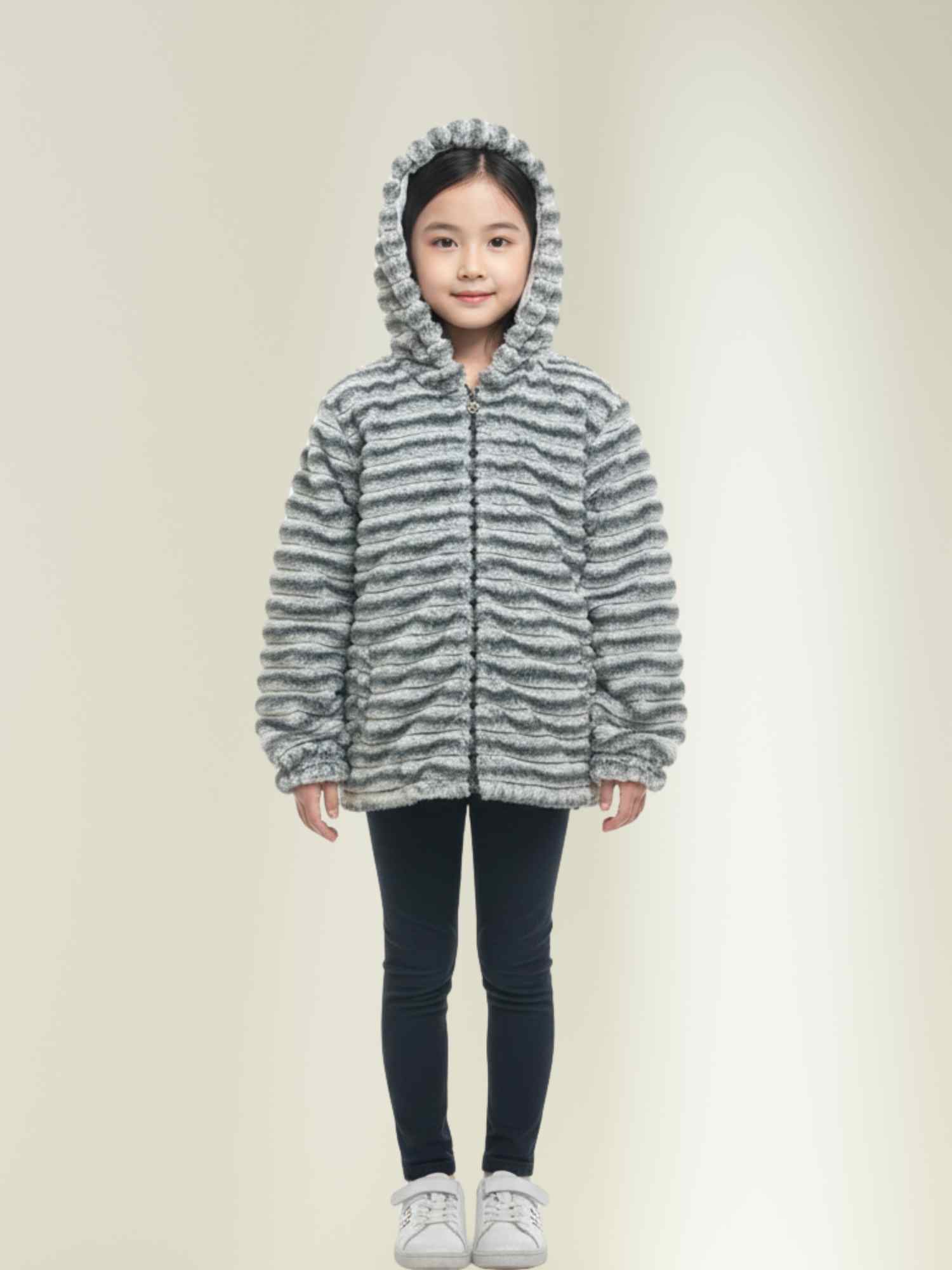 grey faux fur jacket with hood on, winter coat for girls paired with leggings and sneakers.