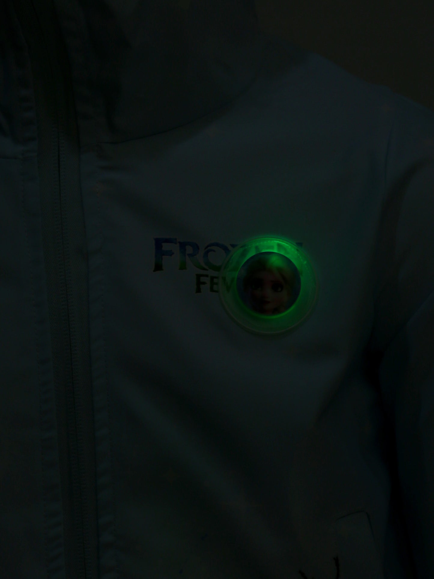 Close-up of a white shirt with a green button featuring a logo and text.
