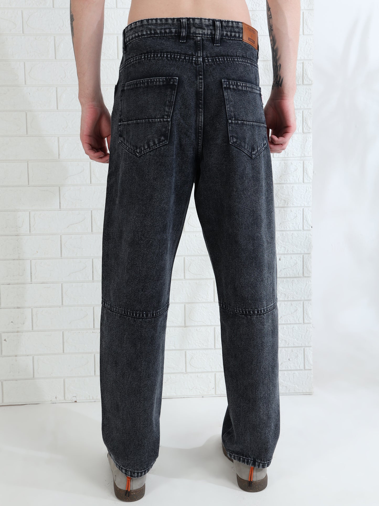 Casual men's washed black jeans paired with sneakers studio look