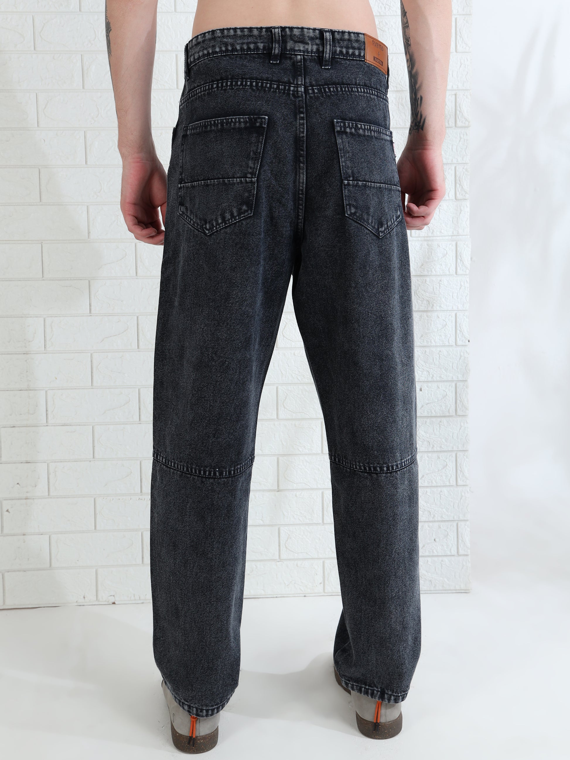 Casual men's washed black jeans paired with sneakers studio look