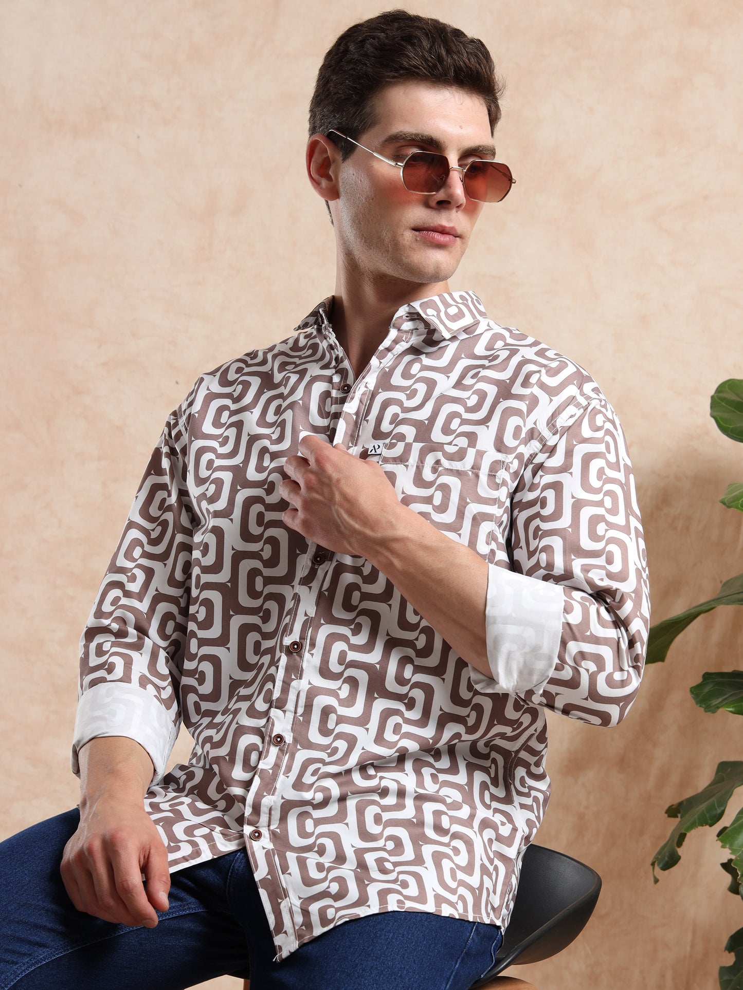 Modern men, printed shirt in brown tones, styled with round sunglasses for a trendy look.