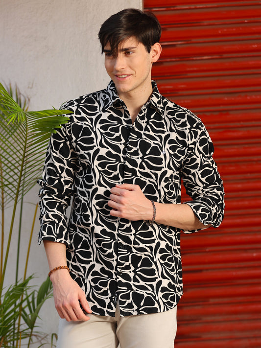A man wearing a black and white dobby printed shirt with full sleeves and a regular fit.
