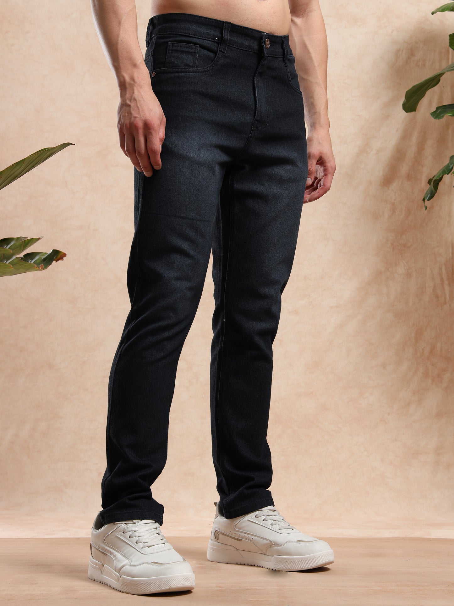 Person wearing black pants and white sneakers against a beige background