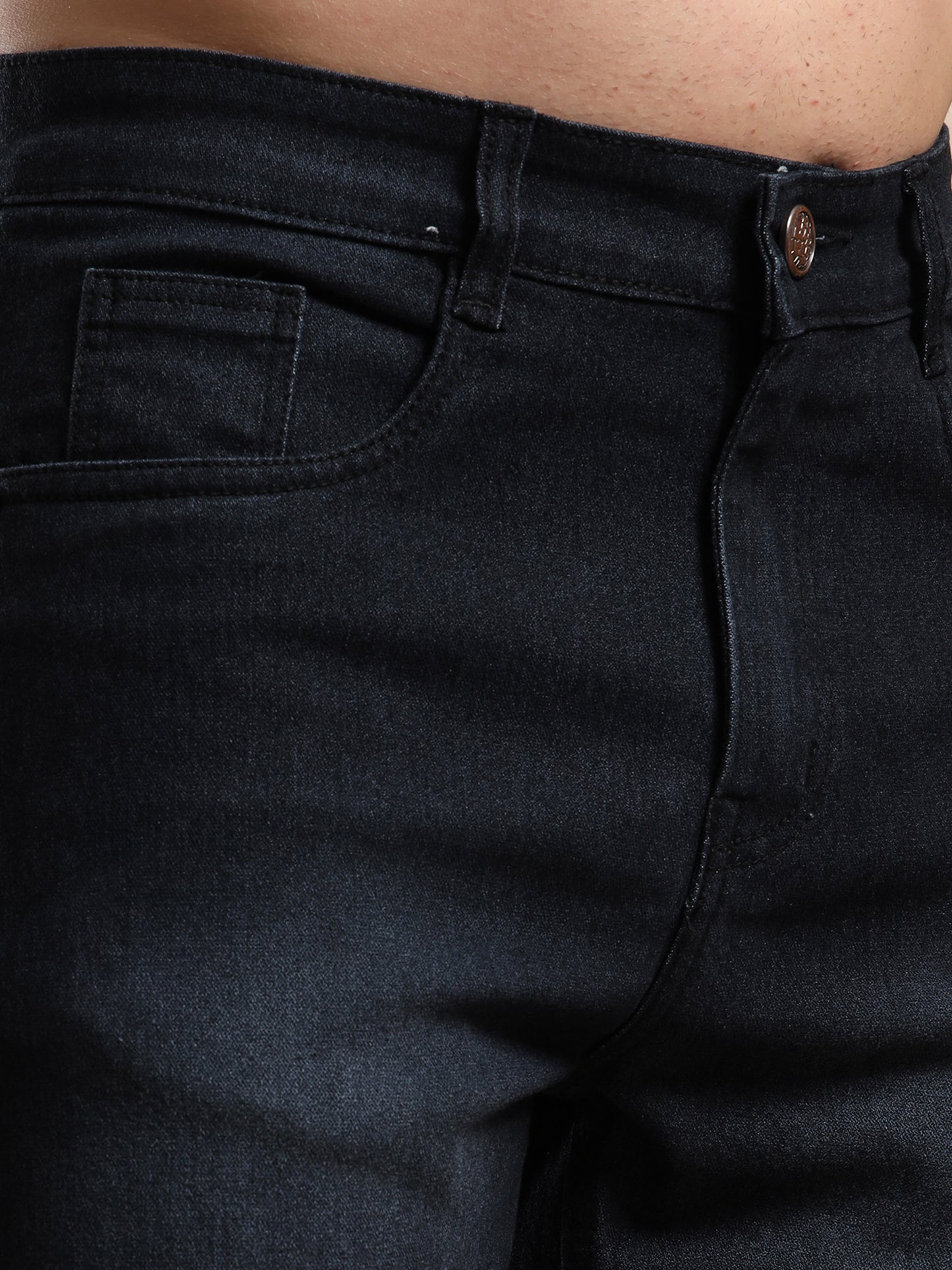 Close-up of black jeans with a focus on the waistband and pocket area.