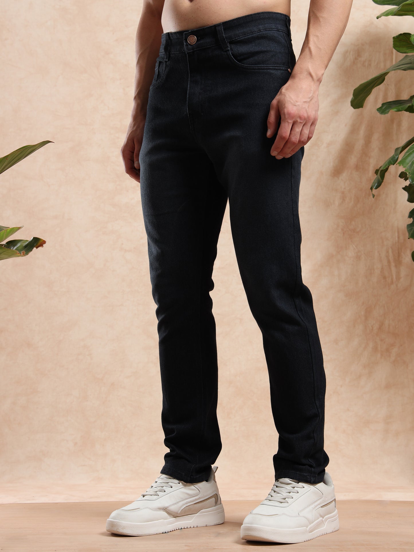 Person wearing black jeans and white sneakers on a beige background