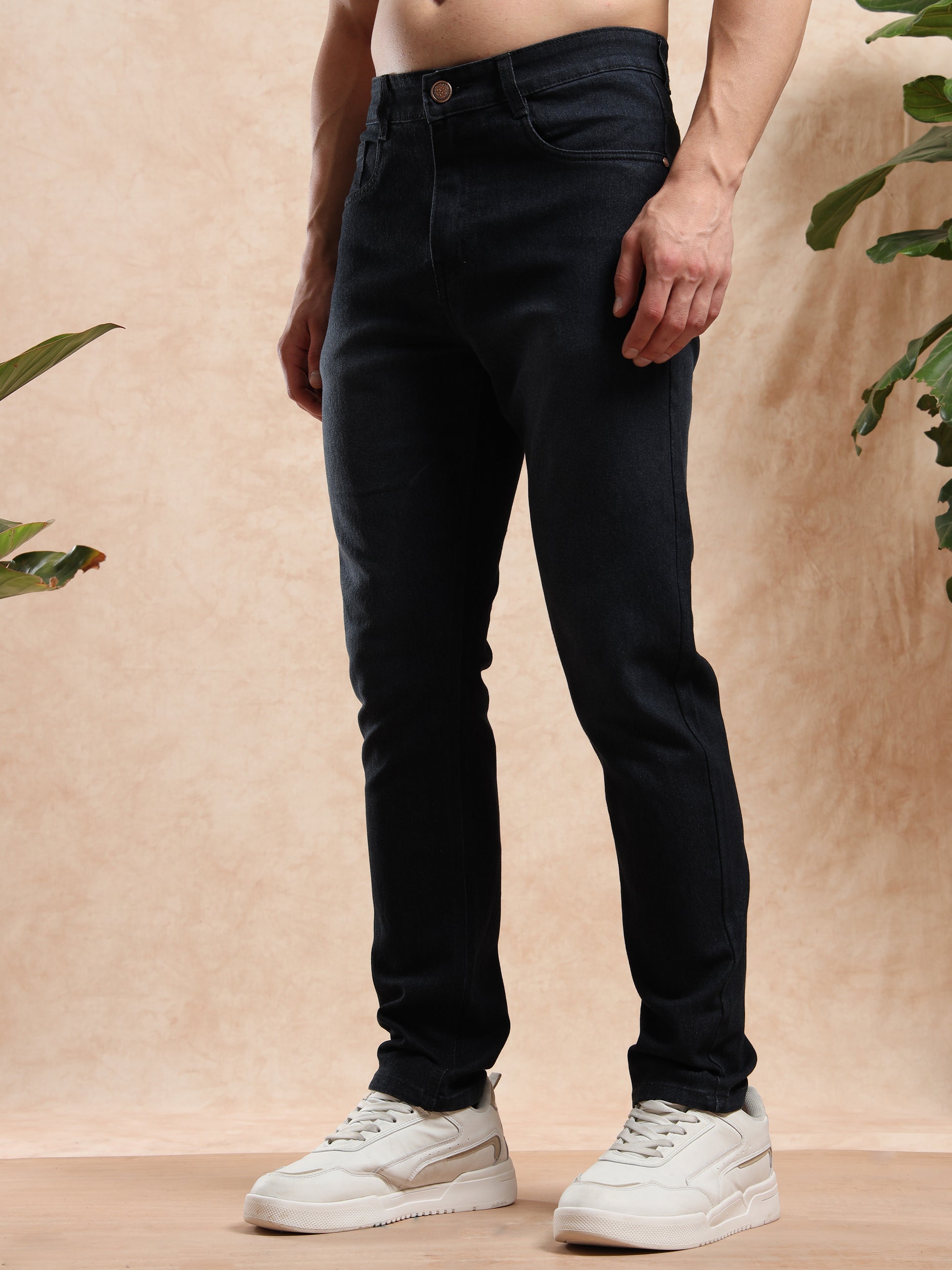 Person wearing black jeans and white sneakers on a beige background