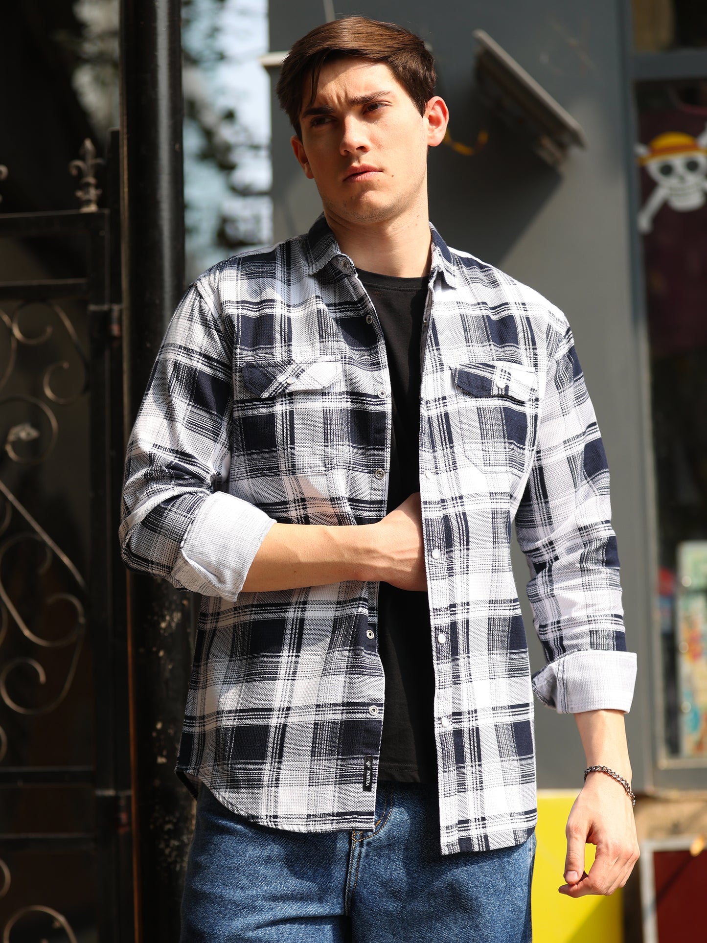 A man wearing a navy blue and white checkered shirt with full sleeves, a regular collar, and two pockets.