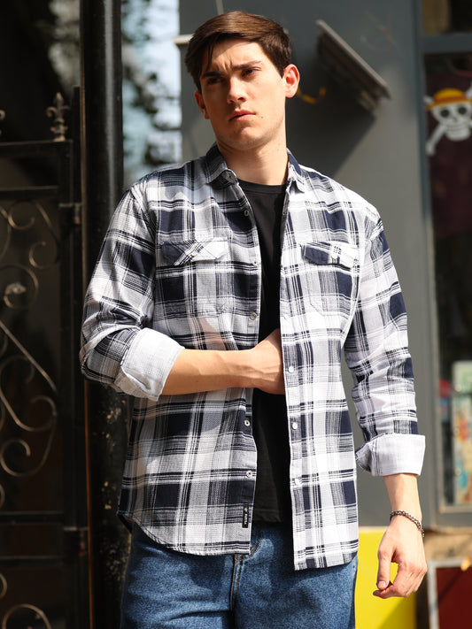 A man wearing a navy blue and white checkered shirt with full sleeves, a regular collar, and two pockets.