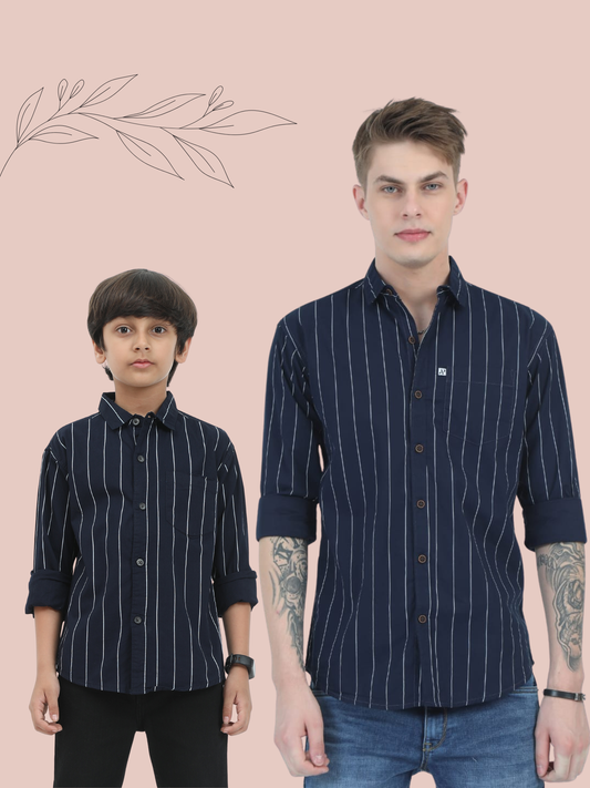 Two individuals wearing matching navy blue shirts with white stripes on a beige background.