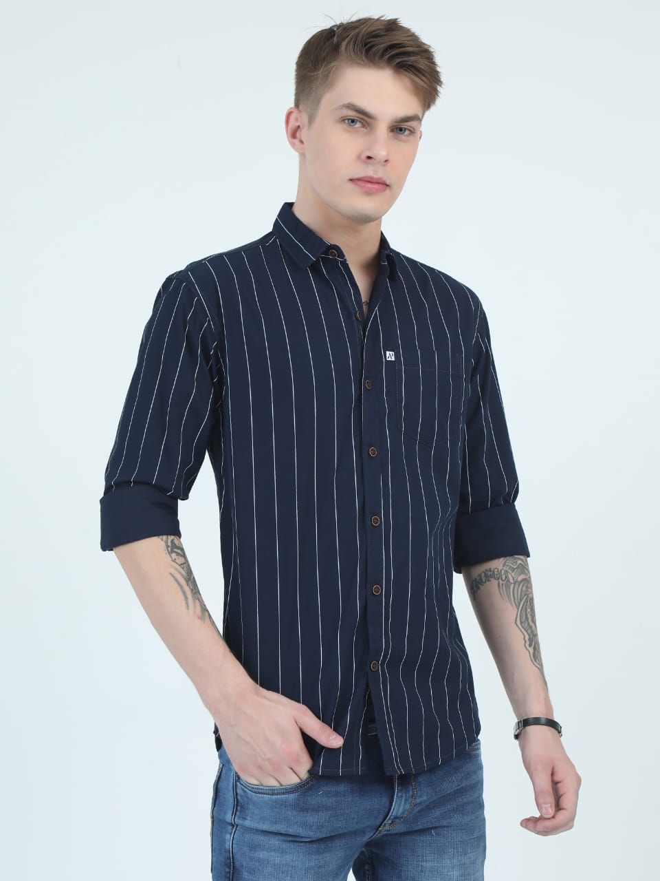 Man wearing a navy blue striped shirt with rolled-up sleeves on a white background
