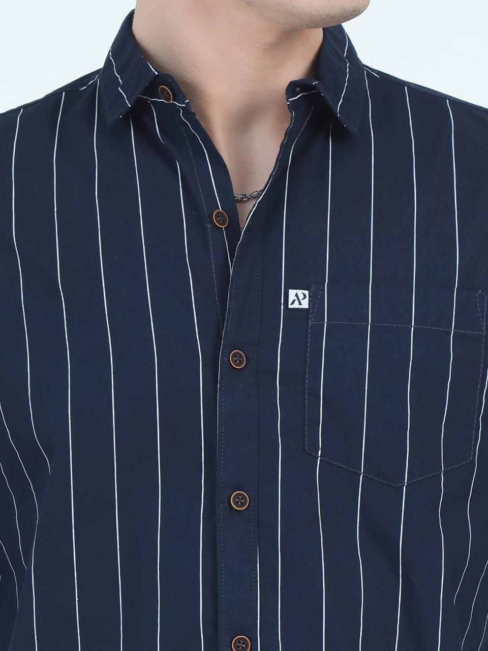Navy blue shirt with white pinstripes and a brand logo on a light gray background