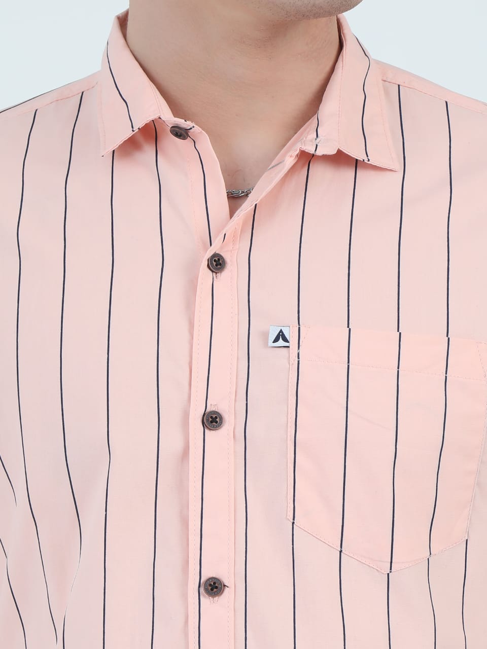 Close-up of a pink shirt with black vertical stripes on a light gray background