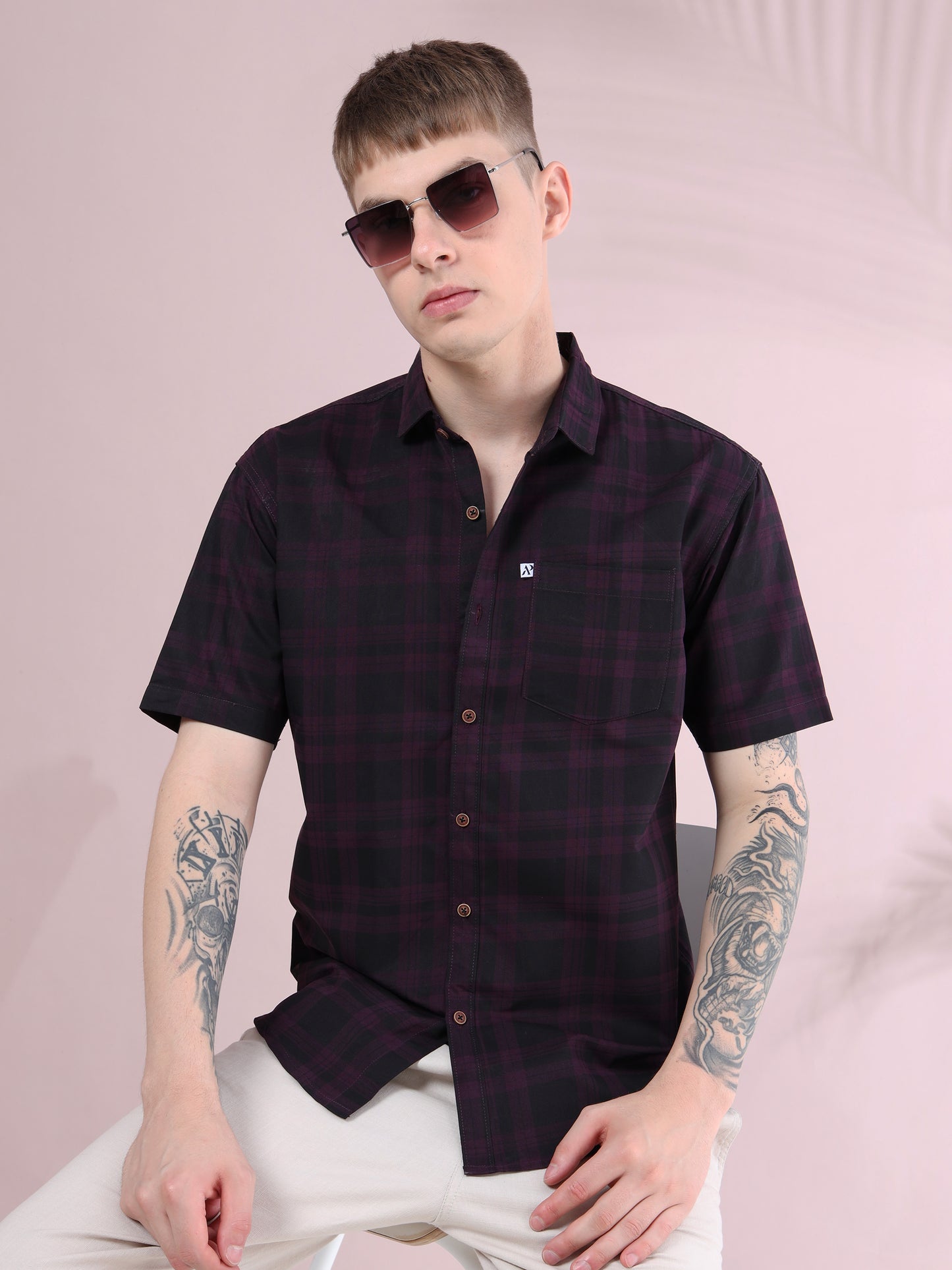 Men purple and black checked short sleeve cotton shirt styled with beige pants, accessorized with sunglasses.