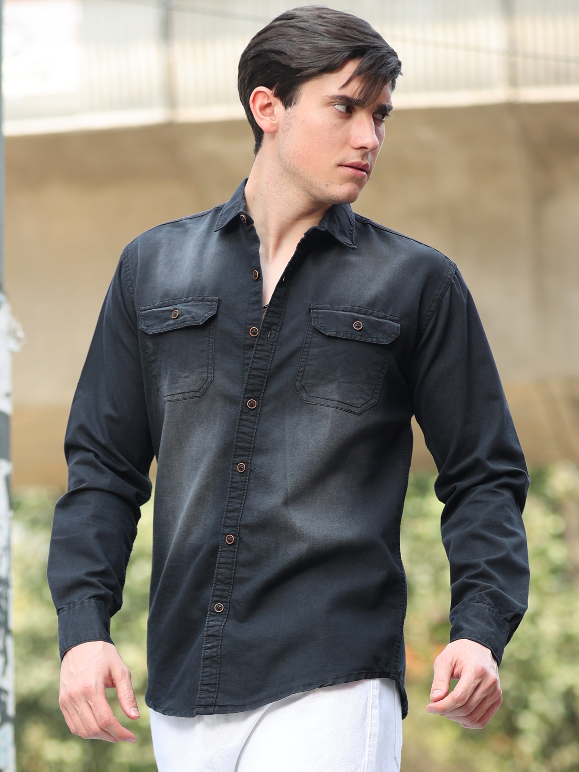 Casual men's black shirt paired with white pants in clean studio background