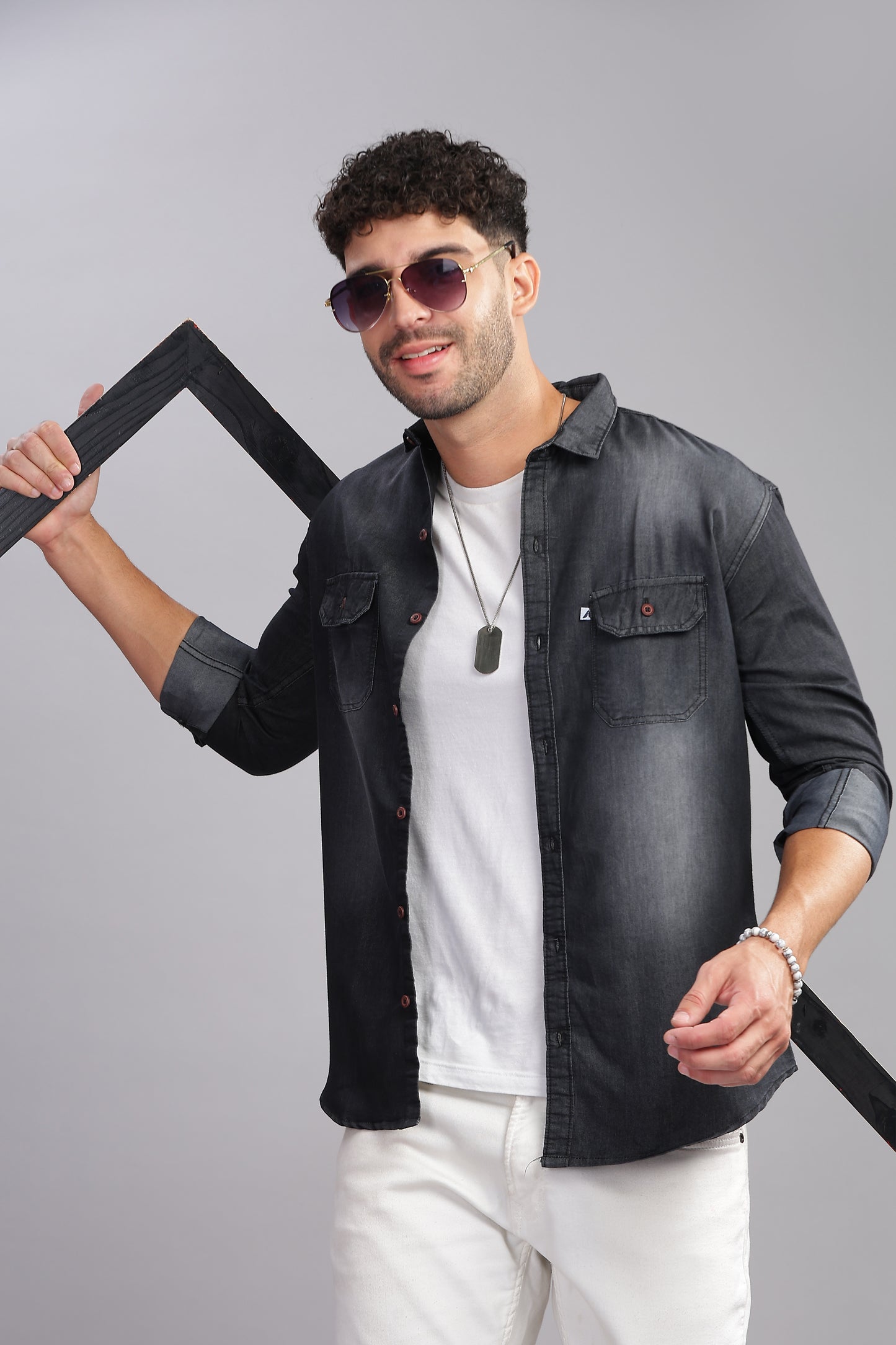Men's black denim shirt with dual chest pockets and rolled-up sleeves on model
