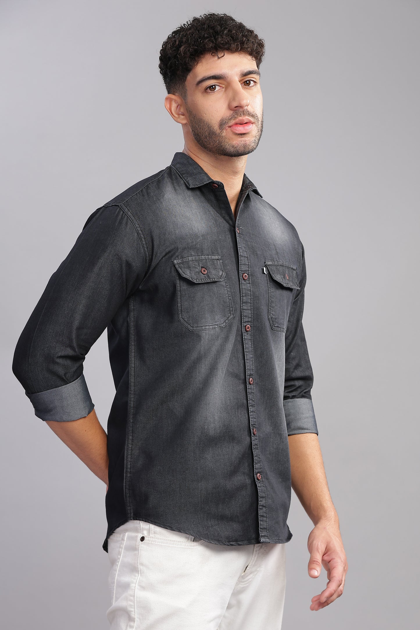 Casual men's black denim shirt outfit with rolled sleeves and clean studio background